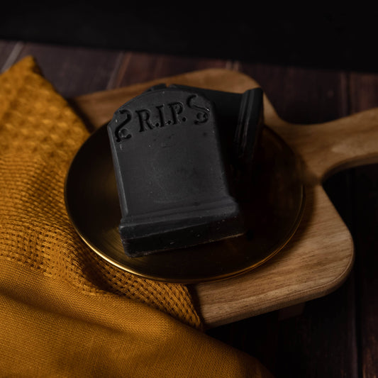 dark grey tombstone shaped soap reading r.i.p. on gold plate
