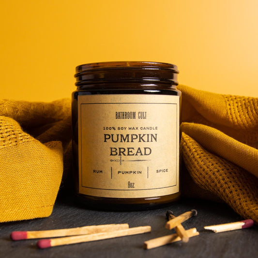 amber glass candle. label reads pumpkin bread: rum, pumpkin, spice